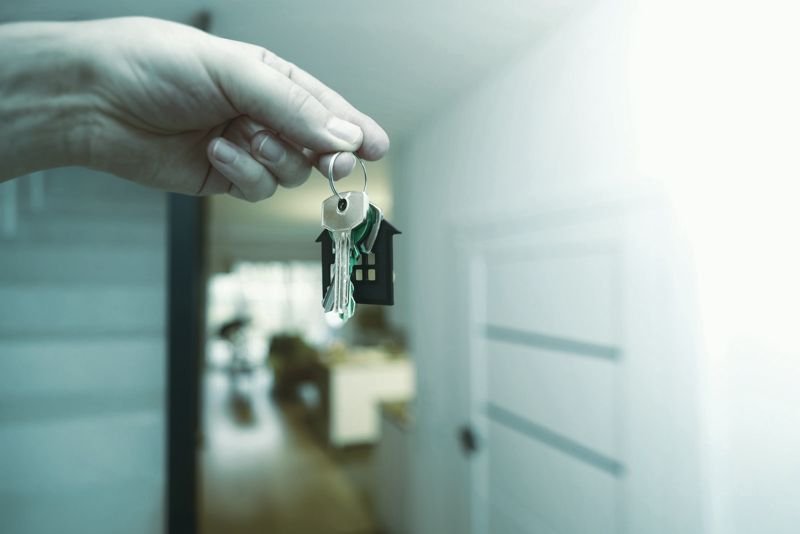 Mano con las llaves de una vivienda en su entrada