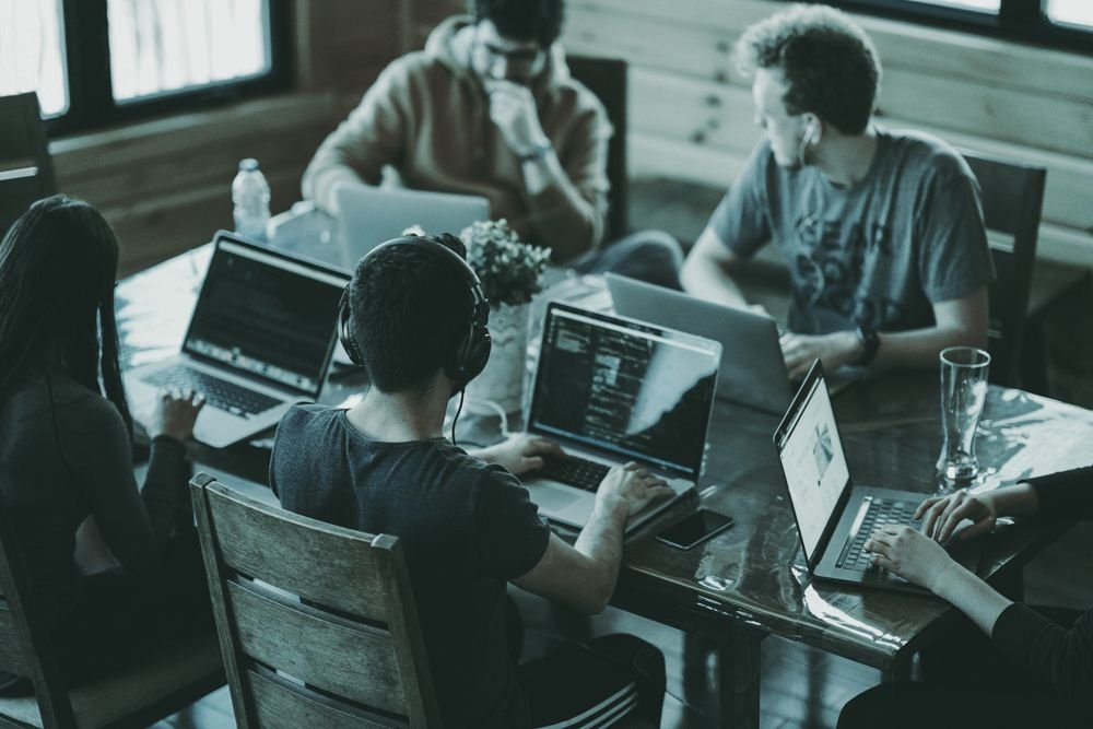 Equipo trabajando junto alrededor de varios portátiles